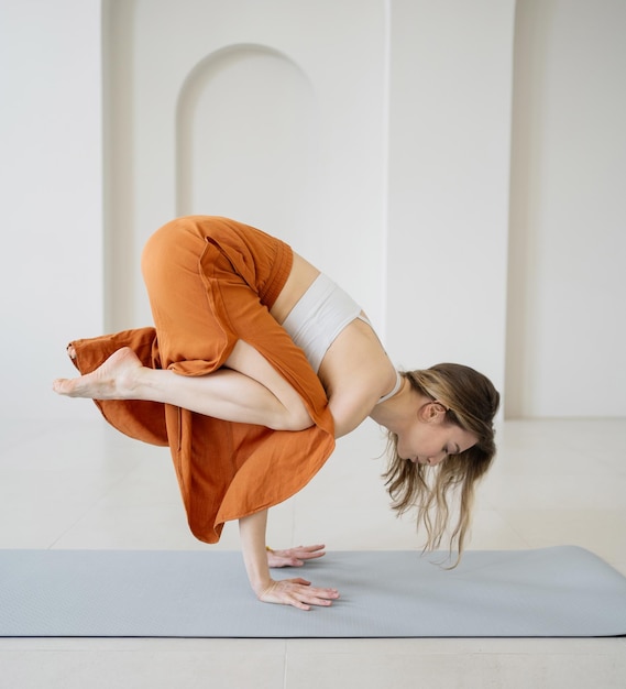 Um treinador feminino faz um treino de ioga pose asana harmonia e equilíbrio do corpo usa um tapete