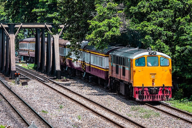 Foto um trem de passageiros atravessa uma ponte sobre o rio.