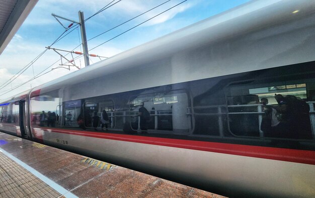 Foto um trem está parando em uma estação com pessoas na plataforma