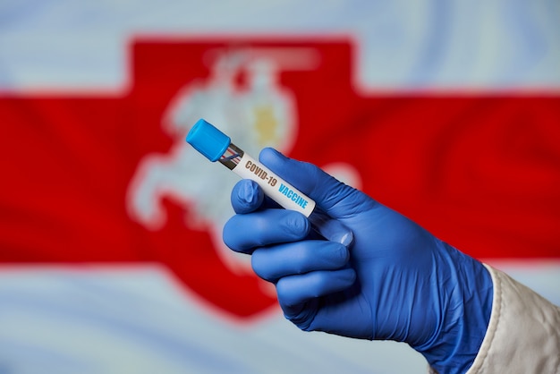 Um tubo de ensaio com uma vacina contra o COVID-19 contra a bandeira da Bielorrússia.