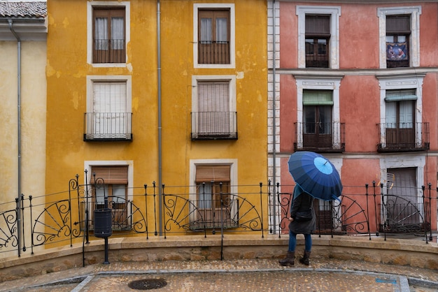Um turista com um guarda-chuva olha para as casas coloridas na cidade velha de Cuenca, Espanha
