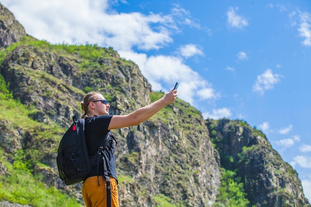 Um turista com um telefone e uma mochila nas montanhas na superfície