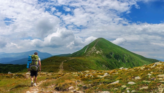 Um turista com uma mochila grande sobe até a montanha mais alta da Ucrânia - a montanha Goverla nas montanhas dos Cárpatos na Ucrânia