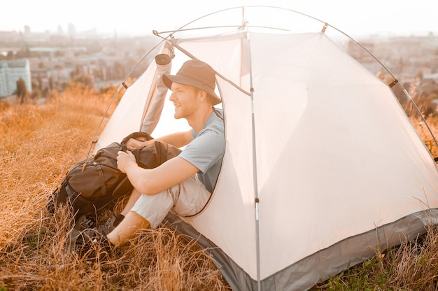 Um turista do sexo masculino sentado perto da tenda e parecendo tranquilo