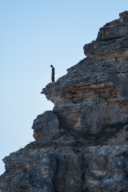 Um turista fica na beira de uma montanha olhando para baixo. viagem de aventura, estilo de vida ativo