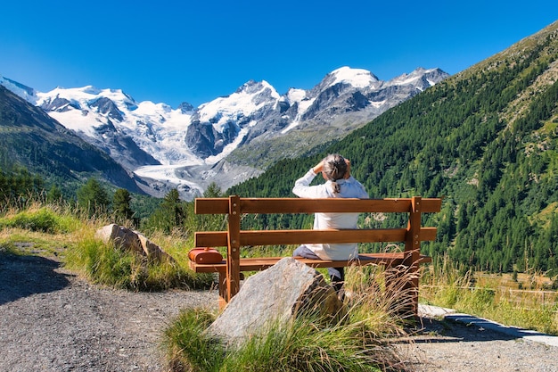 Um turista idoso observa as montanhas com um telescópio de um banco