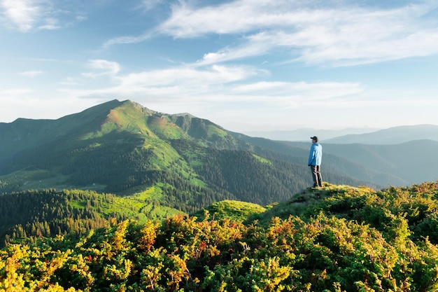 Foto um turista na beira de uma montanha coberta com uma grama exuberante