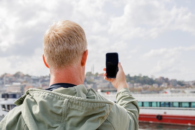 Foto um turista tira um vídeo em seu telefone na frente de uma grande mesquita turca