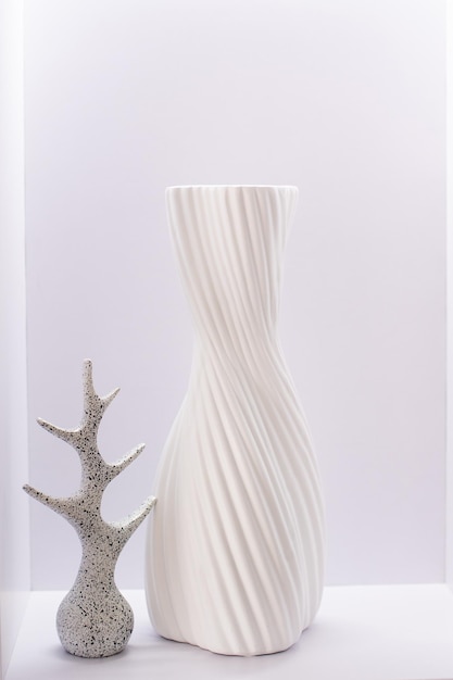 Um vaso branco e um elemento decorativo de pedra ficam em uma prateleira branca