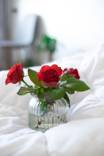 Um vaso de flores está em uma cama com lençóis brancos