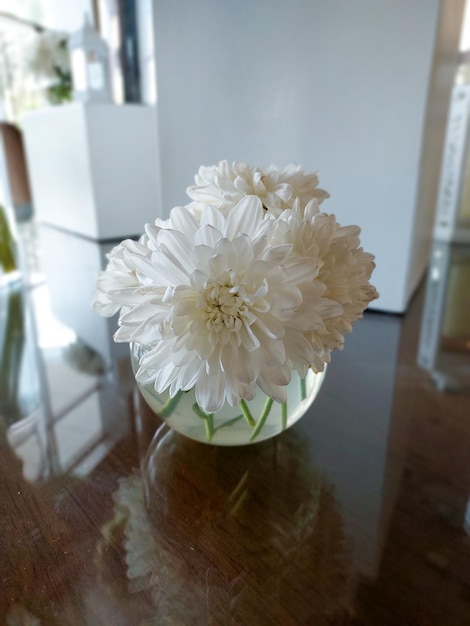 Foto um vaso de flores está sobre uma mesa com uma porta branca atrás dele.