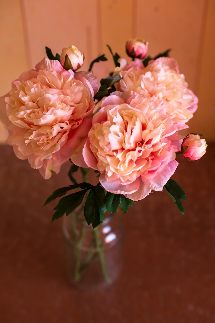 Foto um vaso de flores rosa e brancas com folhas verdes nele.