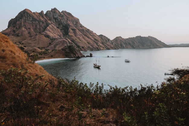 Um veleiro flutuando no mar cercado por colinas perto da Ilha Padar Labuan Bajo