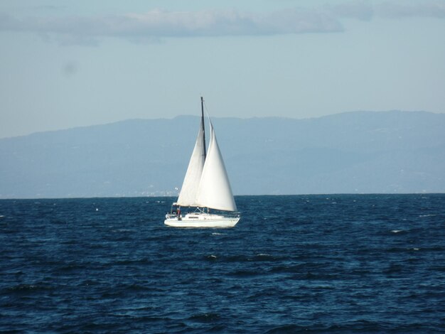 Um veleiro solitário no mar azul calmo contra o céu