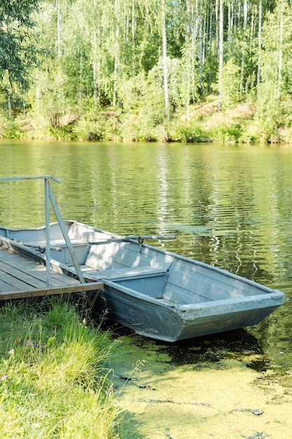 Um velho barco com remos em uma lagoa verde contra o pano de fundo de uma floresta