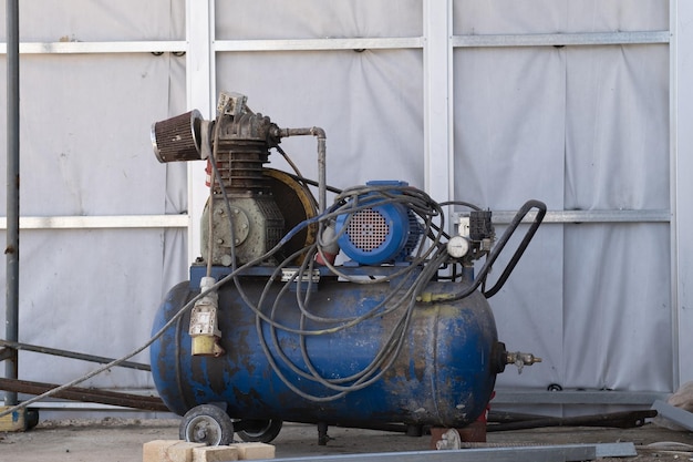 Foto um velho compressor de ar móvel de trabalho azul para pintar paredes em um canteiro de obras equipamento de engenharia