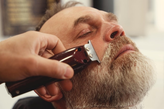 Um velho cortando o cabelo por um mestre em uma barbearia Um velho corta o cabelo estiloso