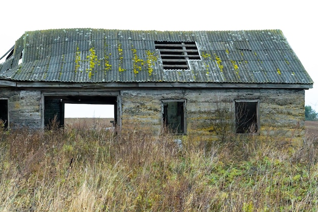 Um velho edifício arruinado sem janelas e portas no meio do campo Paisagem utópica de outono O telhado desabou e coberto de musgo