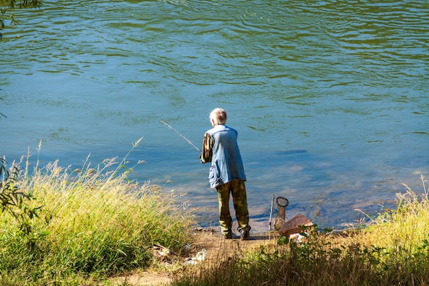 Um velho está pescando, um pescador, passando tempo na natureza.