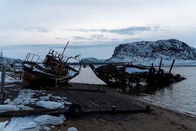 Um velho navio abandonado na costa do Mar de Barents, no Oceano Ártico A vila da península de Teriberka Kola A economia destruída e a indústria do conceito da Rússia