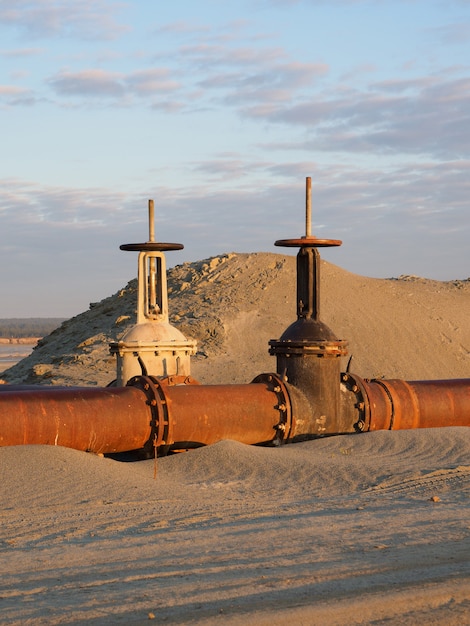 Um velho oleoduto enferrujado no deserto com válvulas. oleoduto para óleo ou gás ao amanhecer. mineração de recursos naturais.