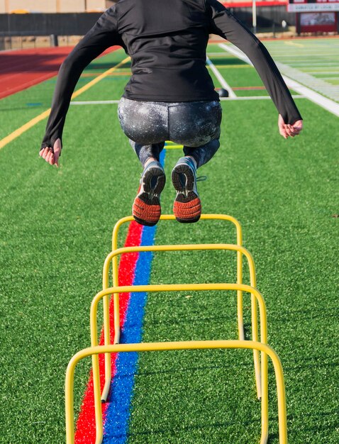 Foto um velocista de atletismo do liceu está a saltar obstáculos de banana amarela.