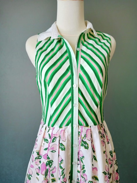 Um vestido verde e branco com flores cor de rosa na frente.