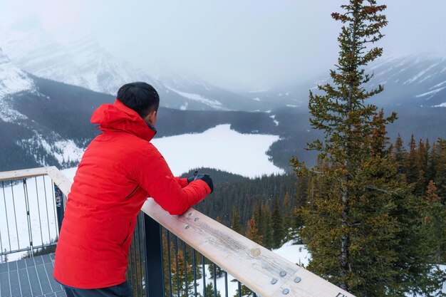 Um viajante de pé e apreciando a vista do lago Peyto semelhante a uma raposa com queda de neve no inverno no parque nacional de Banff