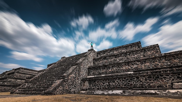 Um viajante de pé no topo da pirâmide de Teotihuacan