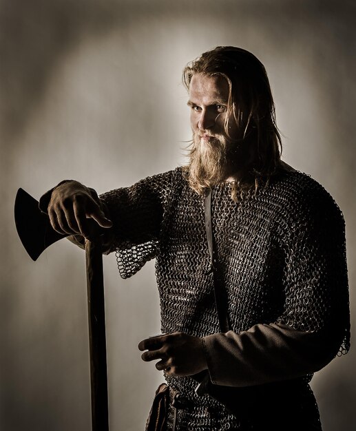 Foto um viking sério com um machado contra a parede.