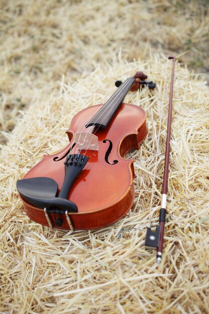 Foto um violino e um arco colocados em uma pilha de palha no campo. treinamento de violino musical