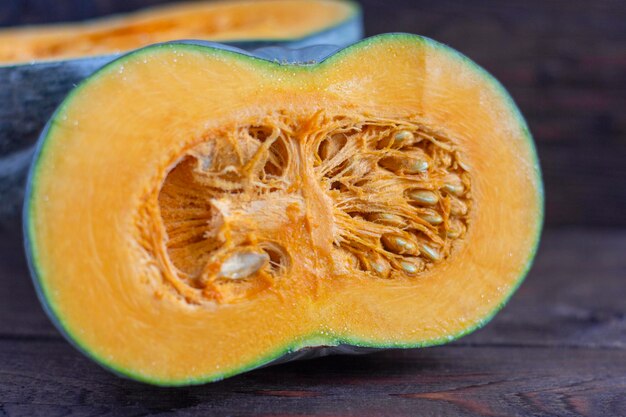 Uma abóbora madura com carne laranja brilhante cortada ao meio em uma velha mesa de madeira