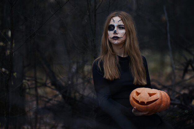 Uma abóbora para o Halloween Uma garota com maquiagem assustadora de Halloween e Calaveras