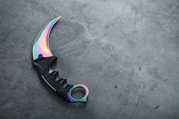 Foto uma adaga com lâmina de aço com um gradiente de cor em um fundo preto. armas afiadas, vista superior, espaço livre