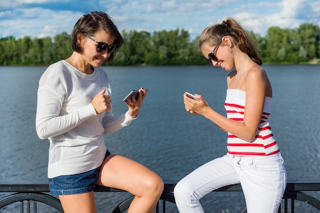 Uma adolescente bonita e mãe usam telefones