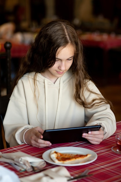 Uma adolescente bonita senta-se em um café com um gadget Comunicação on-line Use gadgets Geração Z