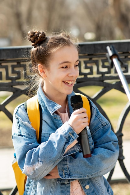 Foto uma adolescente bonitinha com um microfone se apresenta do lado de fora da lifestile city