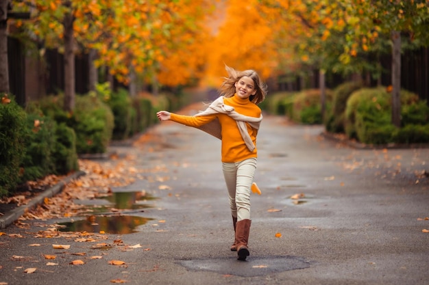 Foto uma adolescente com uma camisola amarela caminha ao longo de uma rua fora da cidade contra o pano de fundo de árvores amarelas divertida caminhada no outono