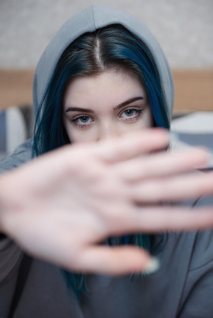 Foto uma adolescente de cabelo azul cobre o rosto com a mão protesto adolescente depressão