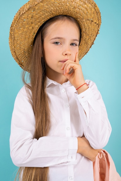 Foto uma adolescente de olhos cinzentos, sorriso bonito e com um chapéu pensa em algo isolado em fundo azul