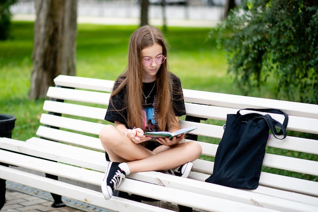 Uma adolescente em um banco com um livro. Educação. Geração Z