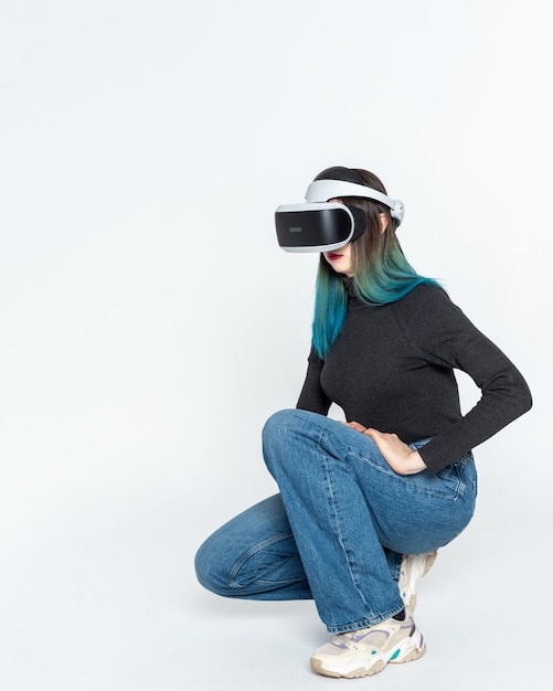 Uma adolescente em um capacete vr joga no universo virtual isolado em um quadro vertical de fundo branco O conceito do universo virtual Estilo de vida no espaço virtual