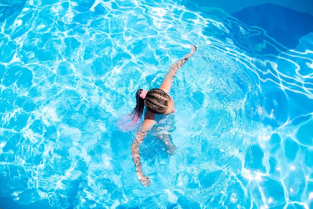 Uma adolescente em uma piscina de água azul férias