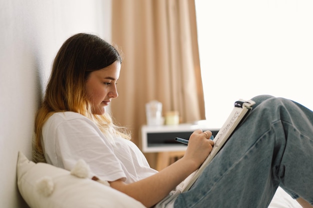 Uma adolescente está desenhando ou fazendo lição de casa no quarto Uma adolescente estuda em casa De volta à escola