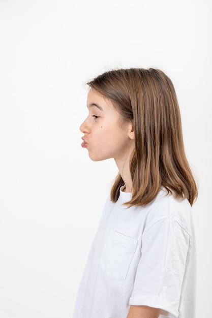 Uma adolescente faz caretas com os lábios apertados em um tubo em um fundo branco