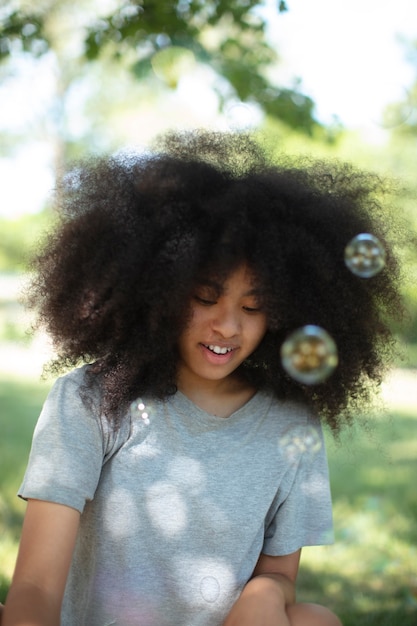 Foto uma adolescente negra brincando com bolhas de sabão