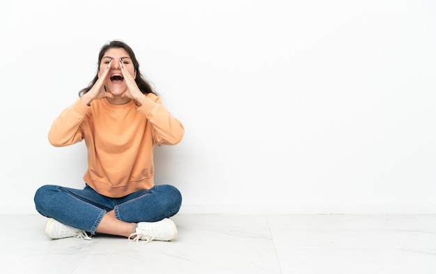 Uma adolescente russa sentada no chão gritando e anunciando algo