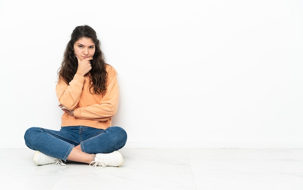 Uma adolescente russa sentada no chão pensando