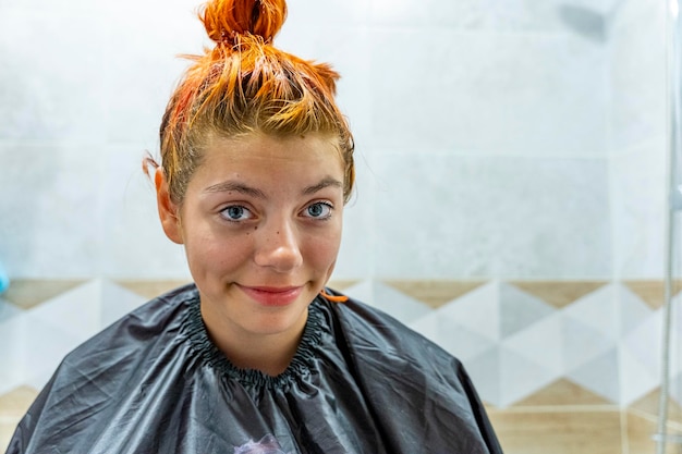 uma adolescente tingi o cabelo de vermelho O processo de tingir o cabelo de vermello Autocolorização do cabelo em casa