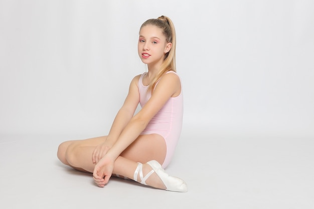 Uma adorável jovem bailarina fazendo poses de balé e exercícios de alongamento no chão em casa